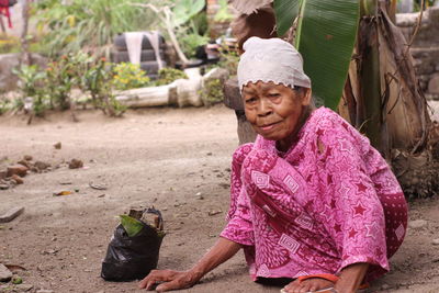 Portrait of senior woman crouching on ground 