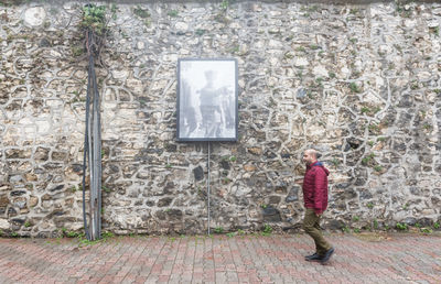 Side view of woman standing against wall