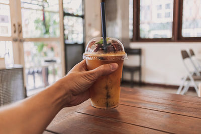 Midsection of person holding drink on table