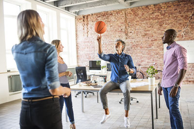 Colleagues playing basketball in office