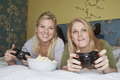 Two young women playing video game in bedroom