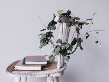 Wreath and books on chair against white wall