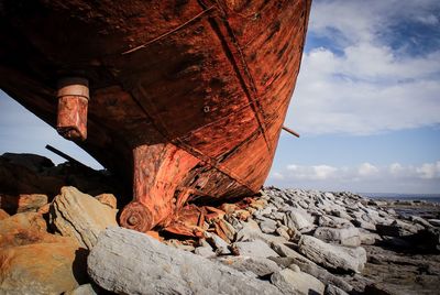 Rusty metal on rock by sea against sky