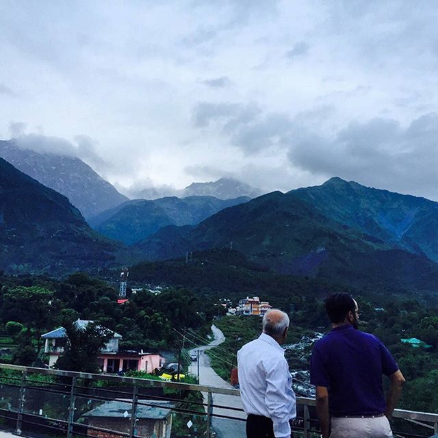 mountain, mountain range, sky, lifestyles, leisure activity, rear view, men, person, cloud - sky, casual clothing, scenics, landscape, nature, sitting, looking at view, beauty in nature, cloud, railing