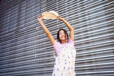 Portrait of young woman standing against wall