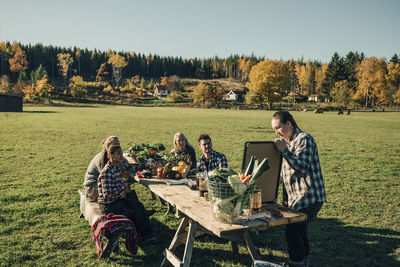 Female instructor showing blackboard to farmers at table on field