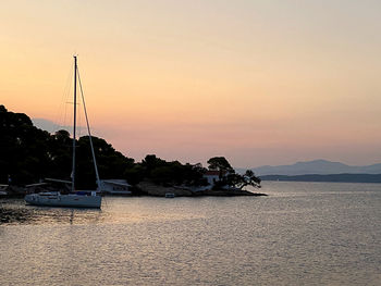 Sailboats sailing in sea against sky during sunset