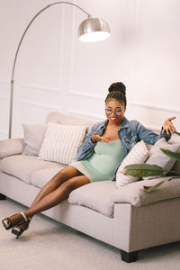 Young woman using mobile phone while sitting on sofa at home