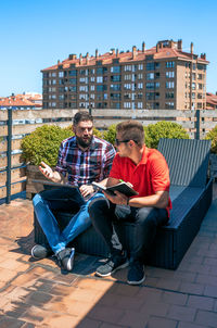 Two colleagues working with laptop sitting on office rooftop