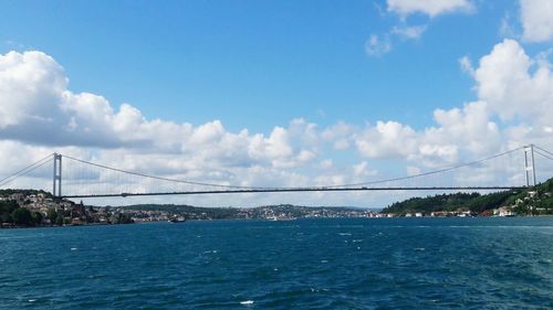 Bridge over river against cloudy sky