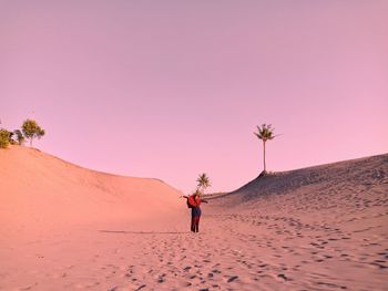 Woman standing on sand dune in desert against sky