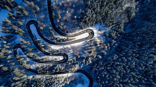 Aerial view of winding road amidst snow covered trees in forest