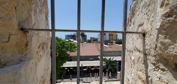 Buildings against sky seen through window