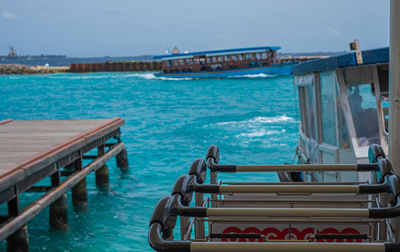 Boat moored on pier by sea against sky