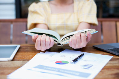 Midsection of man reading book on table