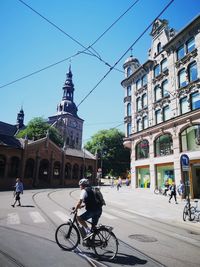 People riding bicycle on city street against buildings