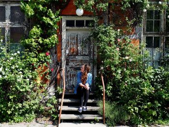 Young woman sitting on front stoop amidst plants