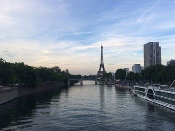 View of city at waterfront against cloudy sky