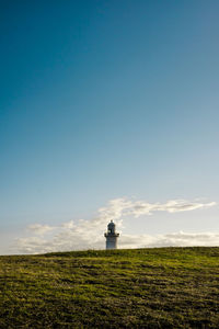 Lighthouse on field against sky