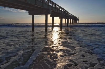 Pier over sea against sky during sunset