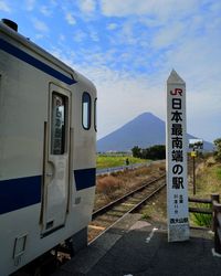 Information sign on railroad tracks against sky