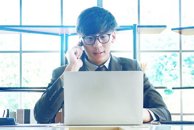 Young man using mobile phone while sitting on table