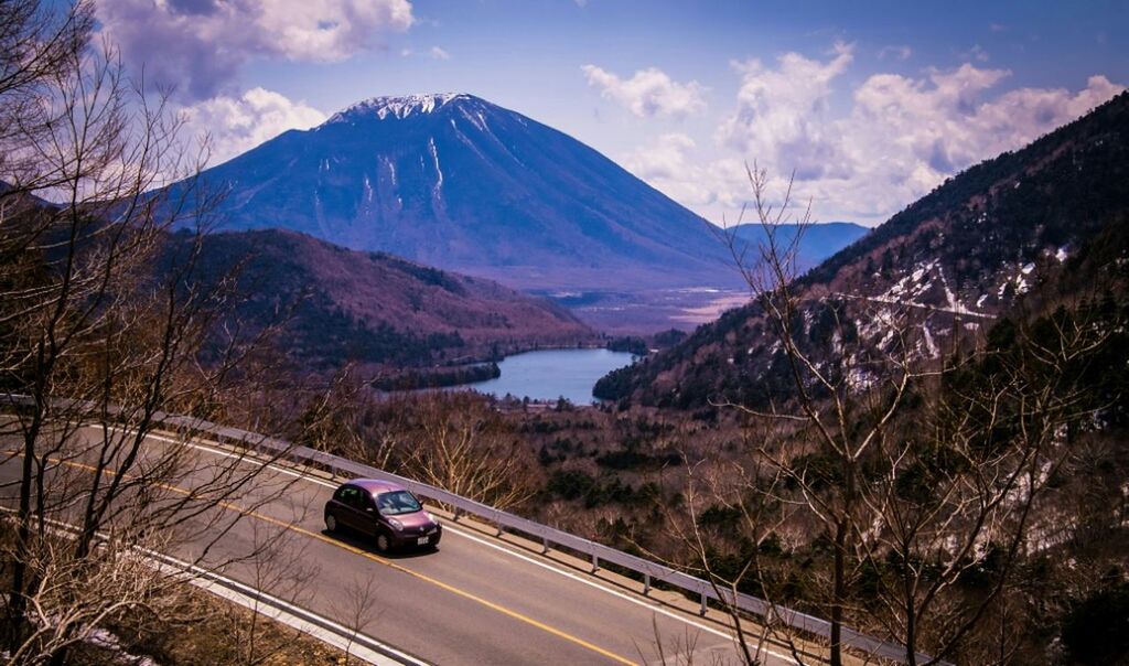 CARS ON ROAD AGAINST MOUNTAINS