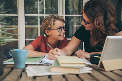 Woman teaching son studying at table