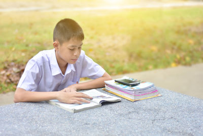 Boy reading book while sitting at marble