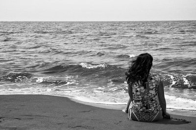 Rear view of woman sitting on beach