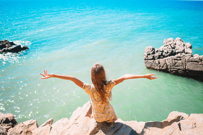 Rear view of woman on rock by sea