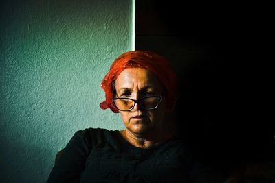 Portrait of woman wearing sunglasses against wall