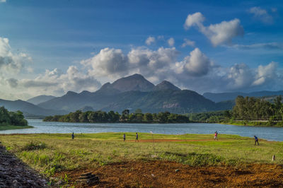 Scenic view of field by sea against sky