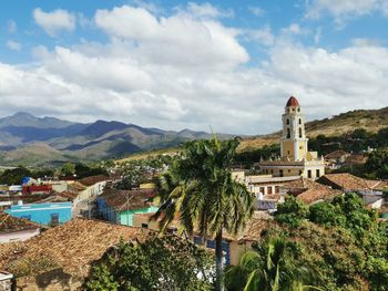 View of trees and buildings against cloudy sky