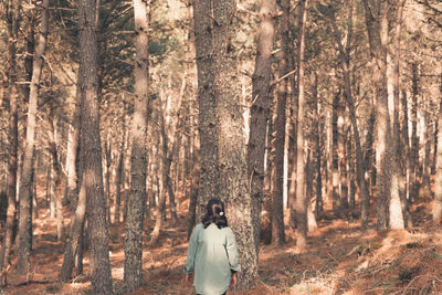 Rear view of woman standing in forest