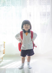 Full length of cute girl standing against curtain