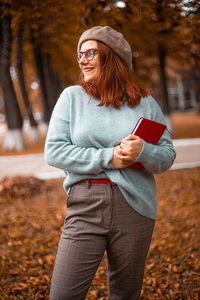 Young woman standing against trees