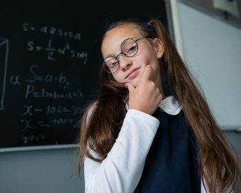 Portrait of young woman standing against wall