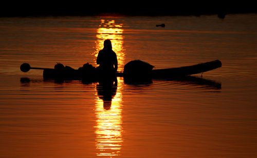 Silhouette men in sea during sunset