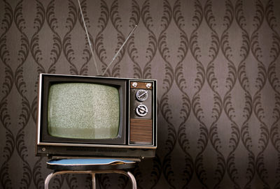 Close-up of old-fashioned television against wall