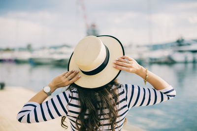 Rear view of woman standing by sea against sky