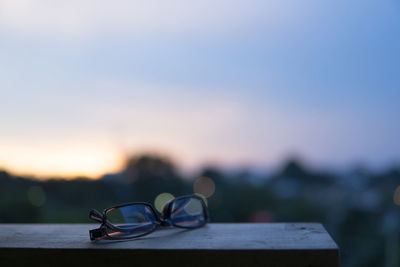 Close-up of sunglasses on land against sky during sunset