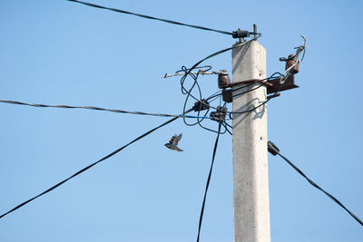 Low angle view of electricity pylon against clear sky