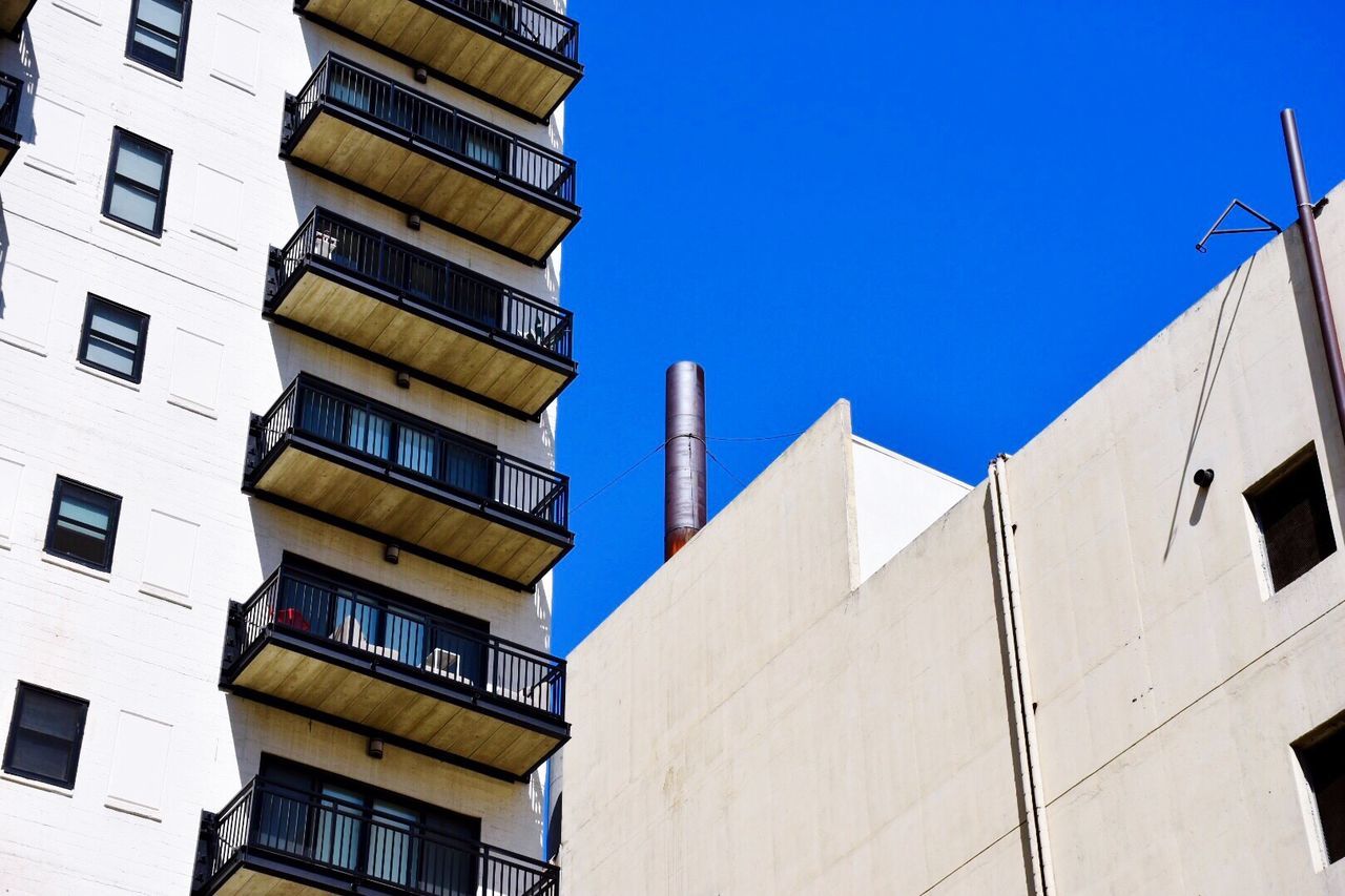 building exterior, architecture, built structure, clear sky, low angle view, building, window, city, residential building, residential structure, apartment, blue, balcony, day, outdoors, in a row, copy space, city life, no people, office building