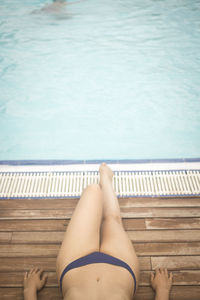 Low section of woman relaxing against swimming pool