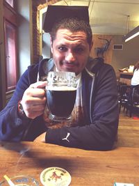 Portrait of a man drinking glass on table