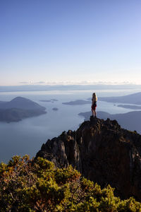 Man standing on rock by mountain against sky