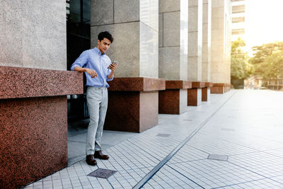 Full length of man standing on footpath in city