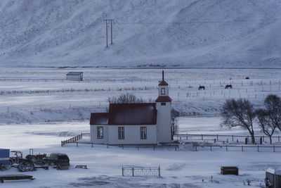 Church on snow covered field against sky