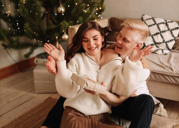 A man and a woman in love embrace give gift gifts celebrate a holiday at the christmas tree at home